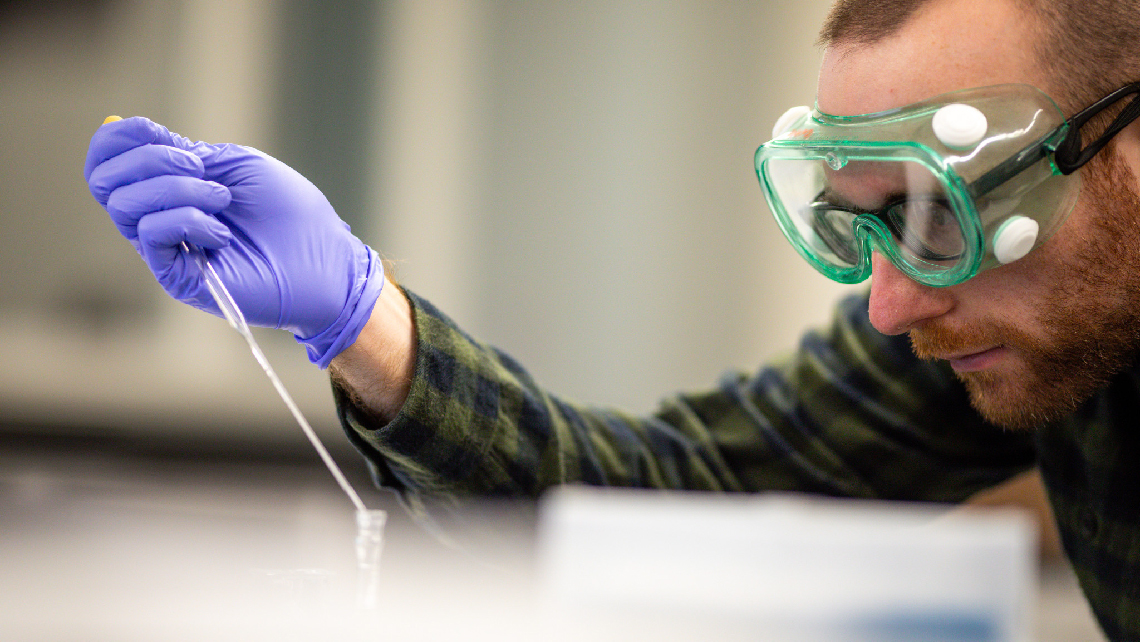 Student using pipette in lab.