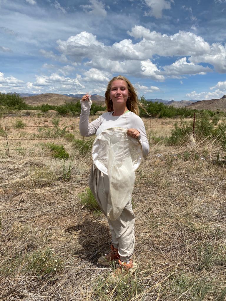 Natalie Herbison in a field with a bee catching net and vial.