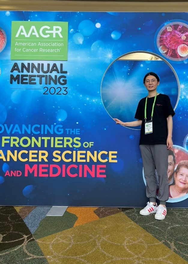 Qi Zhang stand in front of the conference photo backdrop