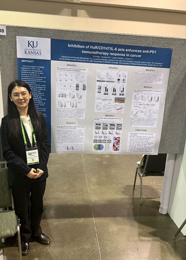 Qi Zhang stands with their research poster